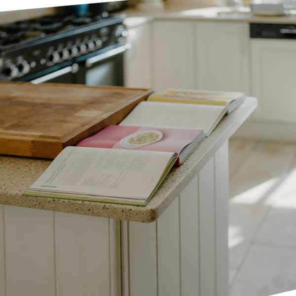 Two open cookbooks resting on a wooden kitchen counter