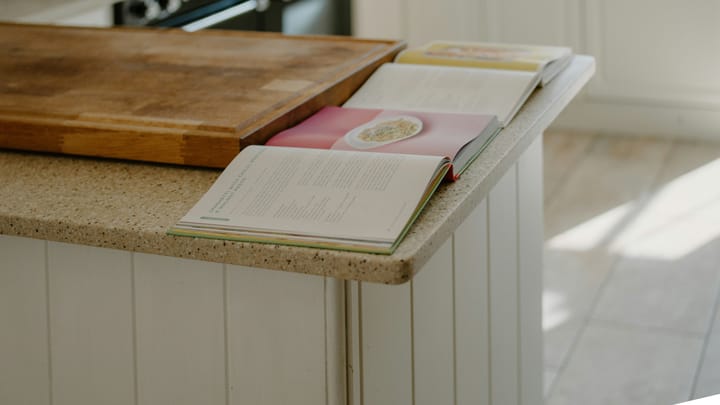 Two open cookbooks resting on a wooden kitchen counter