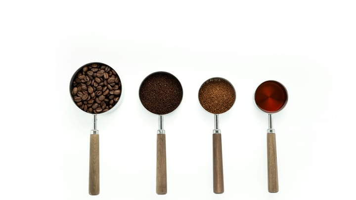Four measuring cups with wooden handles in a row on a white table