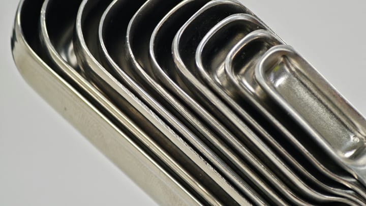 Set of stainless steel measuring spoons nested together on a white surface