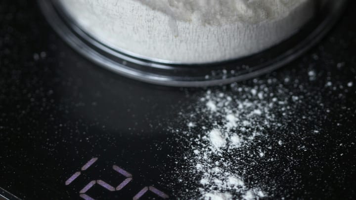 Container of white flour on a black digital kitchen scale showing 125.0